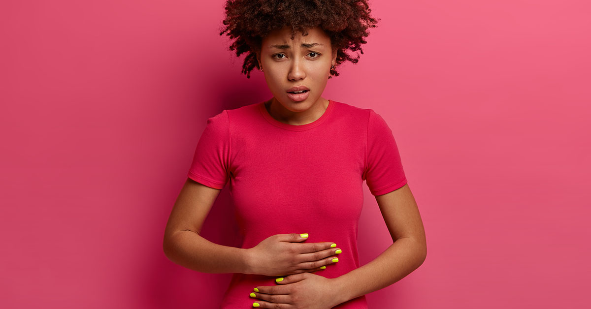 Unhappy African American female feels unwell, has stomach ache because of food poisoning, abdominal main, menstruation period cramp, nausea, painful diseases and diarrhea, grimaces from pain; blog: What Are the Signs of Uterine Fibroids?